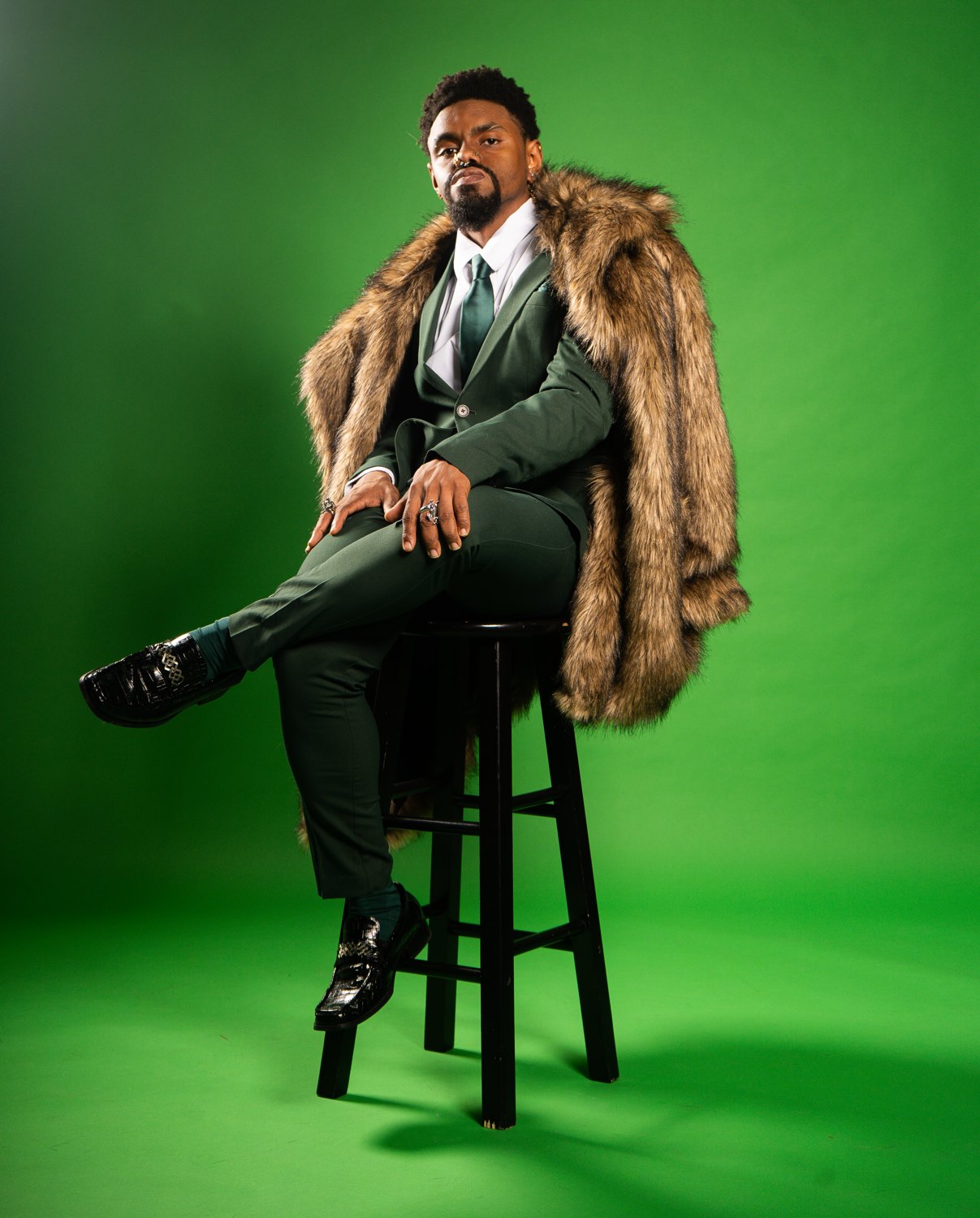 Mal Best, vocal instructor, seated in a tailored green suit